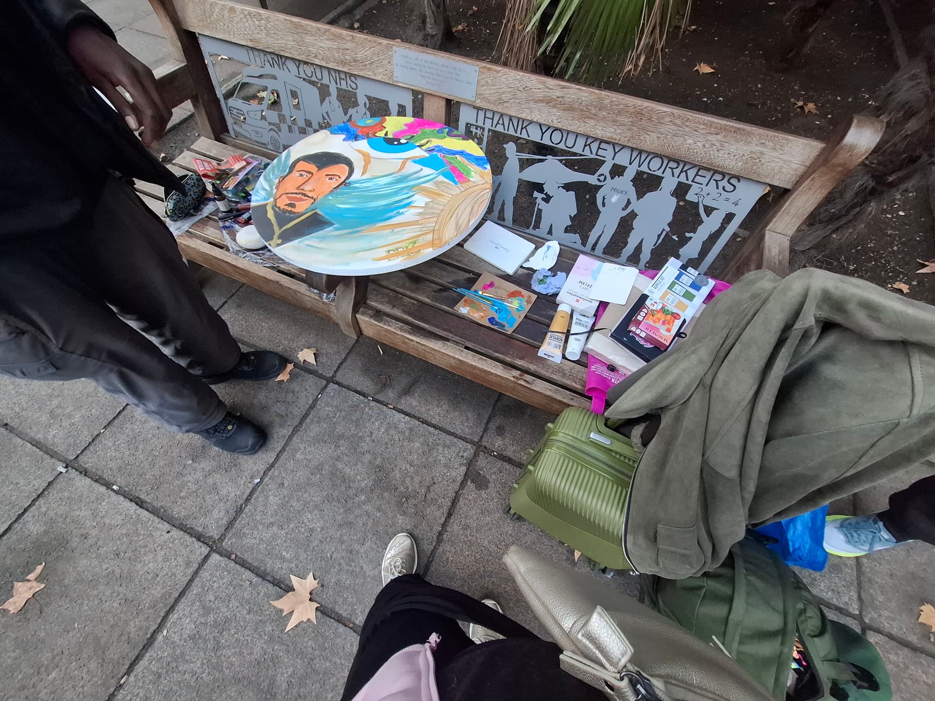 The first round canvas and paints laid out on a park bench